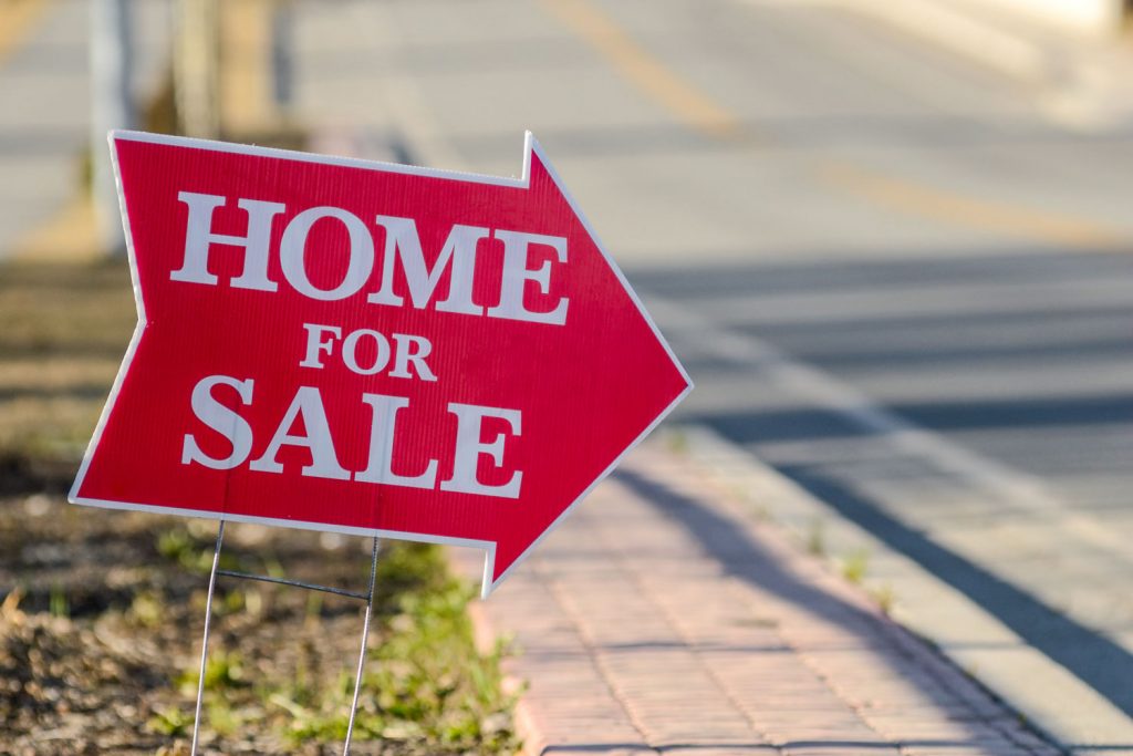 A home for sale sign on the side of the street