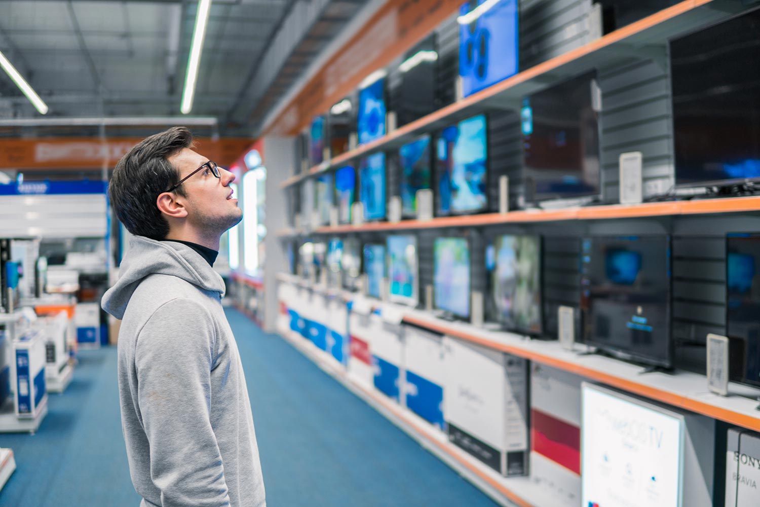 Male customer choosing large TV-sets on sale at Lowes hardware store