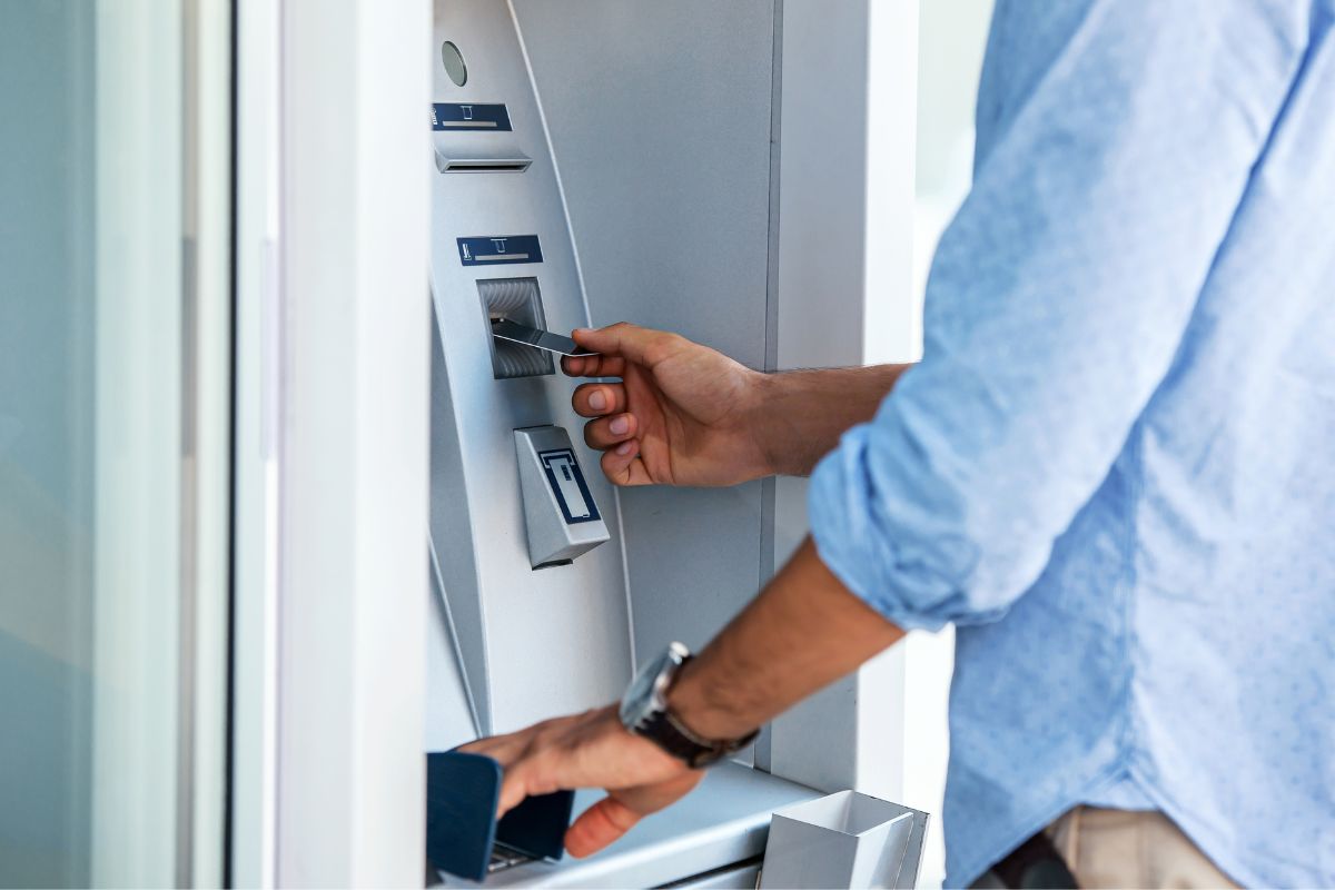 Man using a street ATM machine and withdrawing money, close up photo