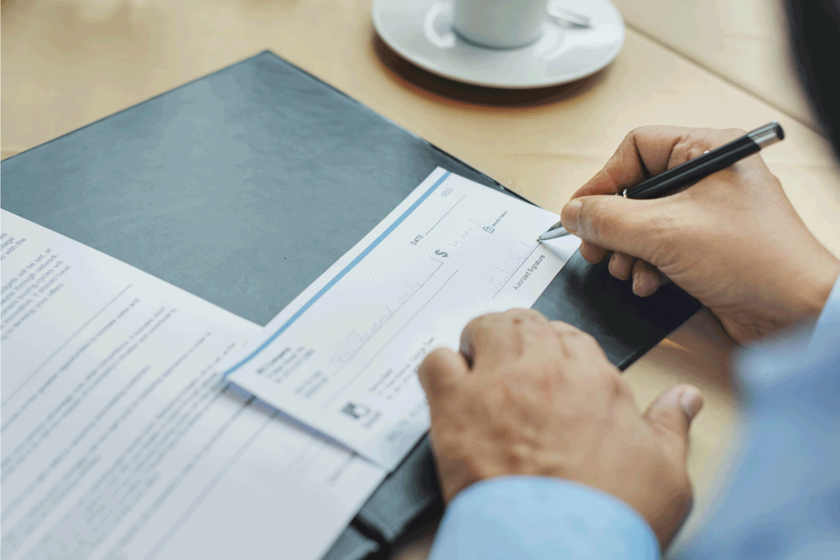 businessman issuing check, using black permanent pen. Can You Write On A Printed Check [Is It Better To Sign One Virtually]